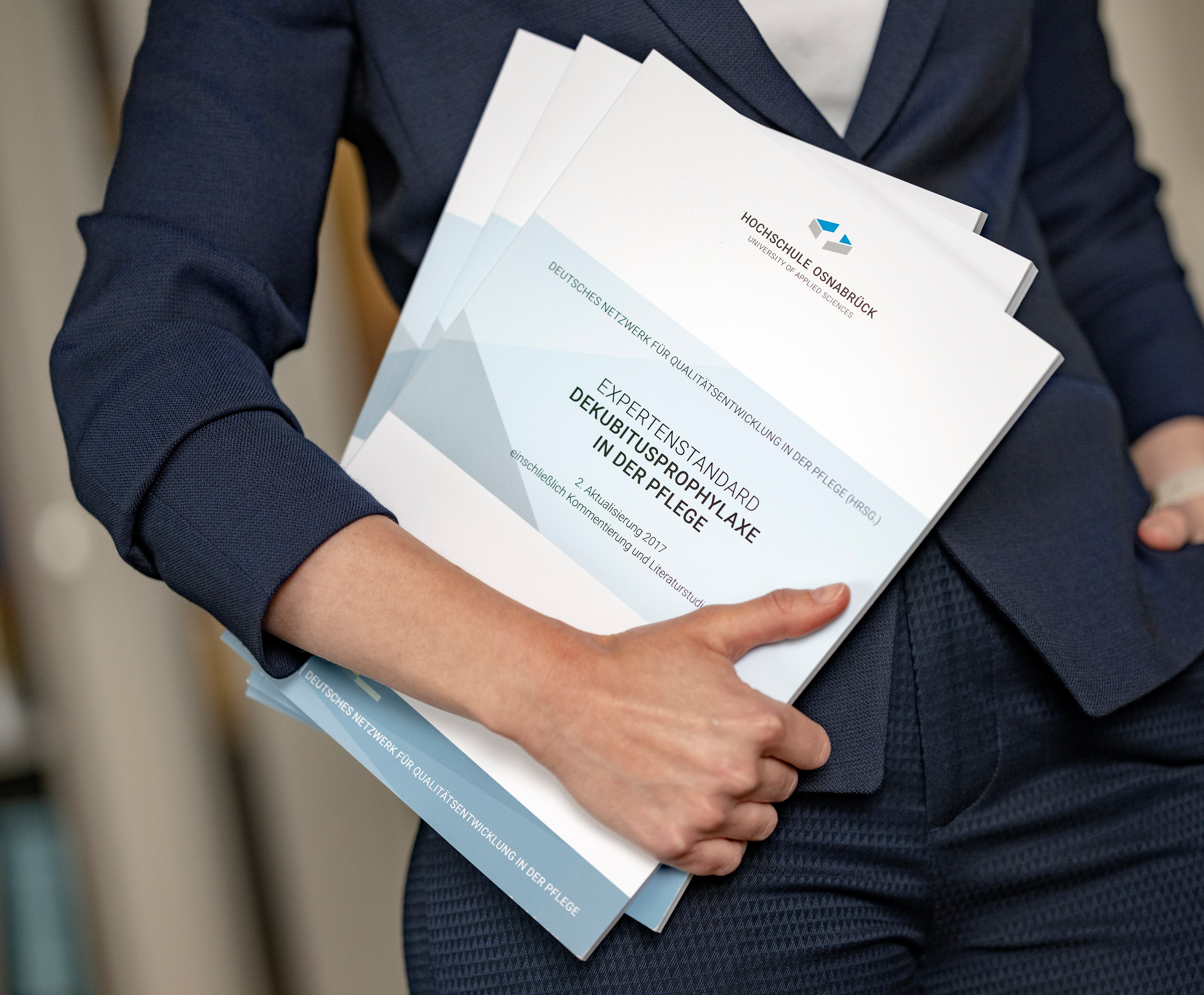 Person hält Expertenstandard in der Hand vor dem Körper